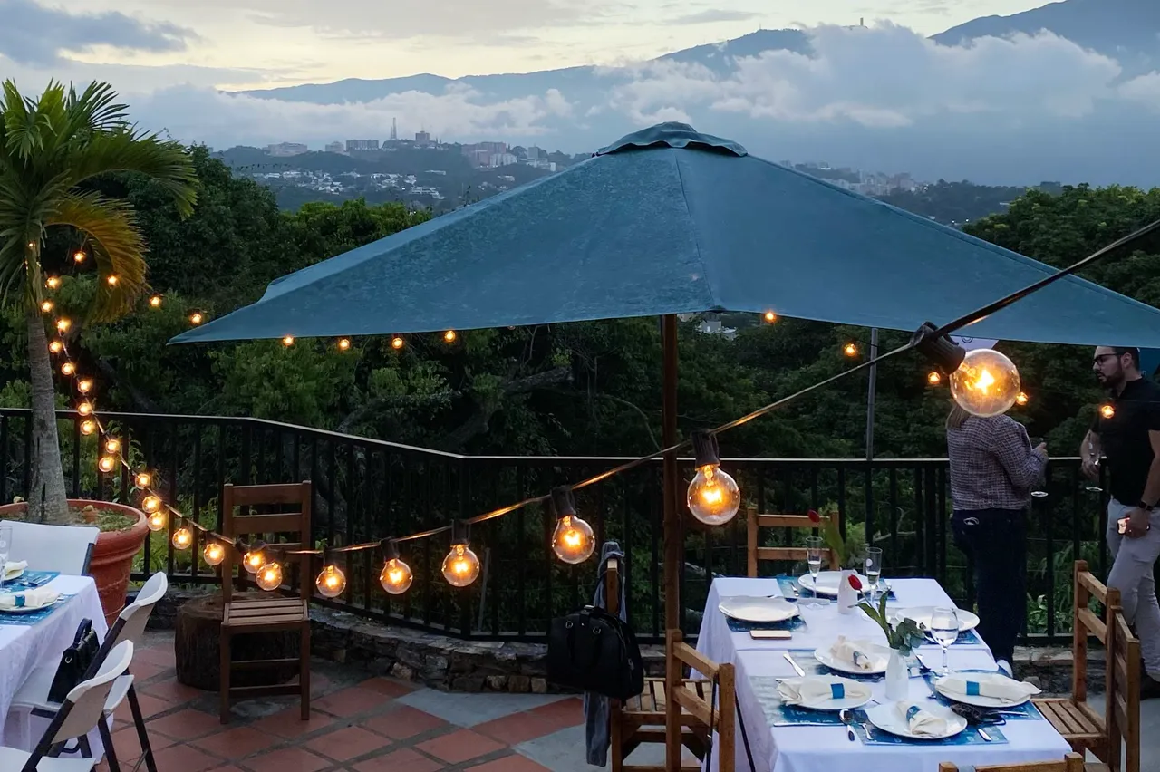 Terrace dinner table under string lights at sunset